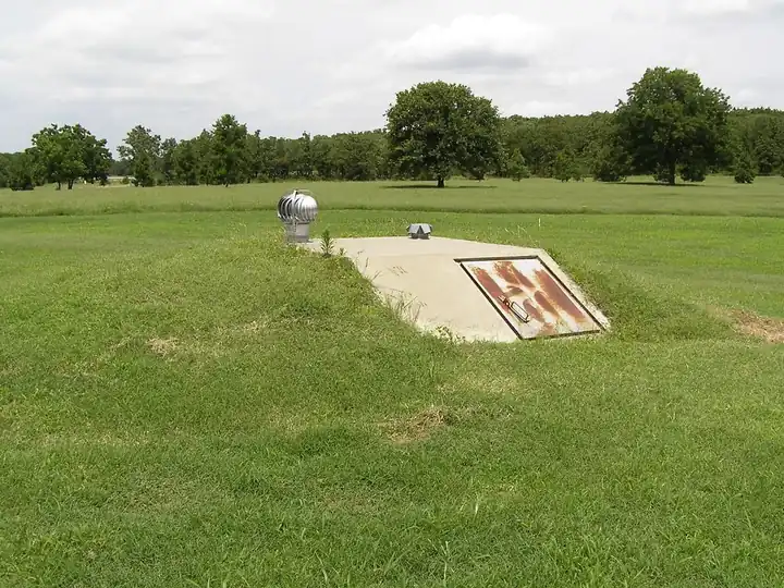 Outdoor in-ground storm shelter with a steel hatch in a back yard